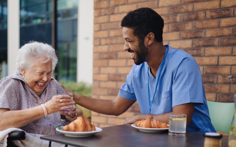 Caregiver having breakfast with his client at cafe.