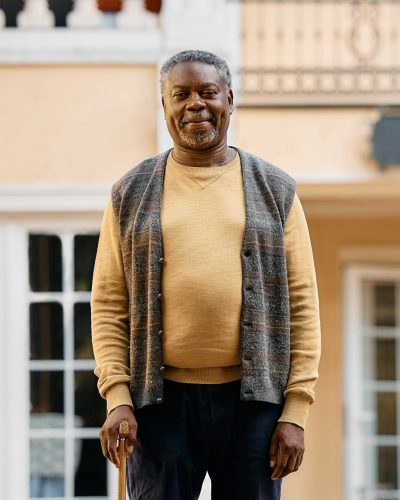 Portrait of black elderly man in front of residential care home.